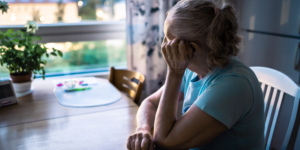 Sad old woman. Depressed lonely senior lady with alzheimer, dementia, memory loss or loneliness. Elder person looking out the home window.