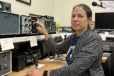 woman sitting at a table with various radio equipment