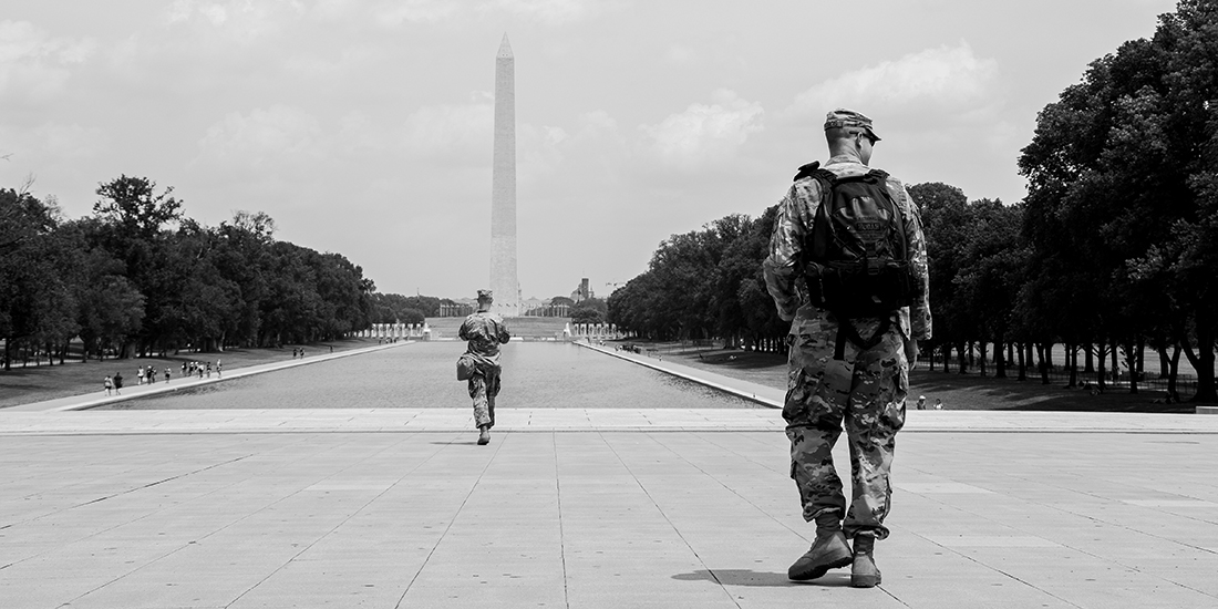 Two soldiers in fatigues walking toward the Washington Monument