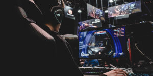 Person sitting at a desk with headphones on facing a gaming computer