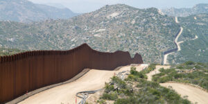mexican border, fence on left with woodsy mountain ahead