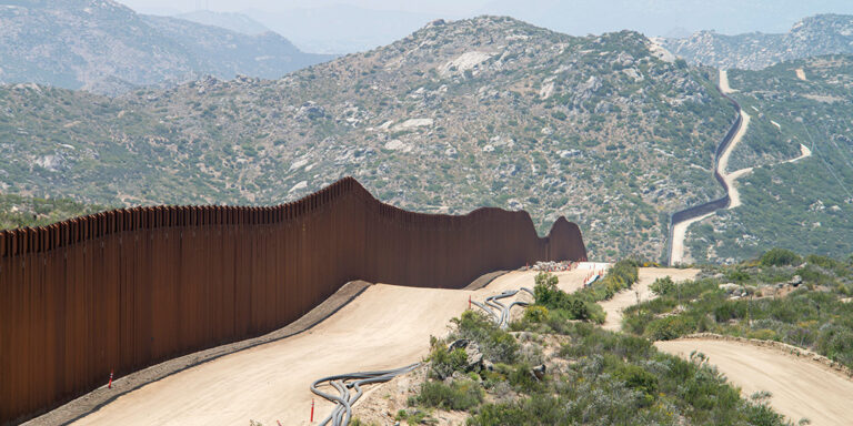 mexican border, fence on left with woodsy mountain ahead
