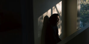woman sitting in dark room by window