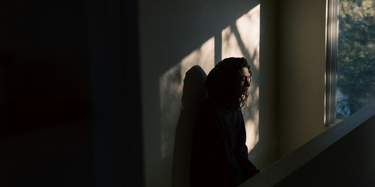 woman sitting in dark room by window
