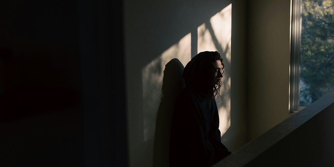woman sitting in dark room by window