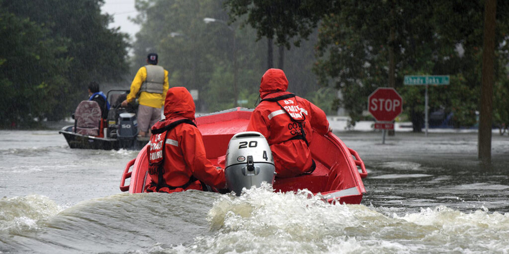 Coast Guardsmen in an inflatable motor boat motoring down a flooded street