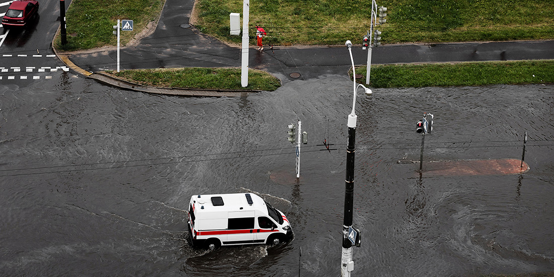 ambulance is driving along a flooded road